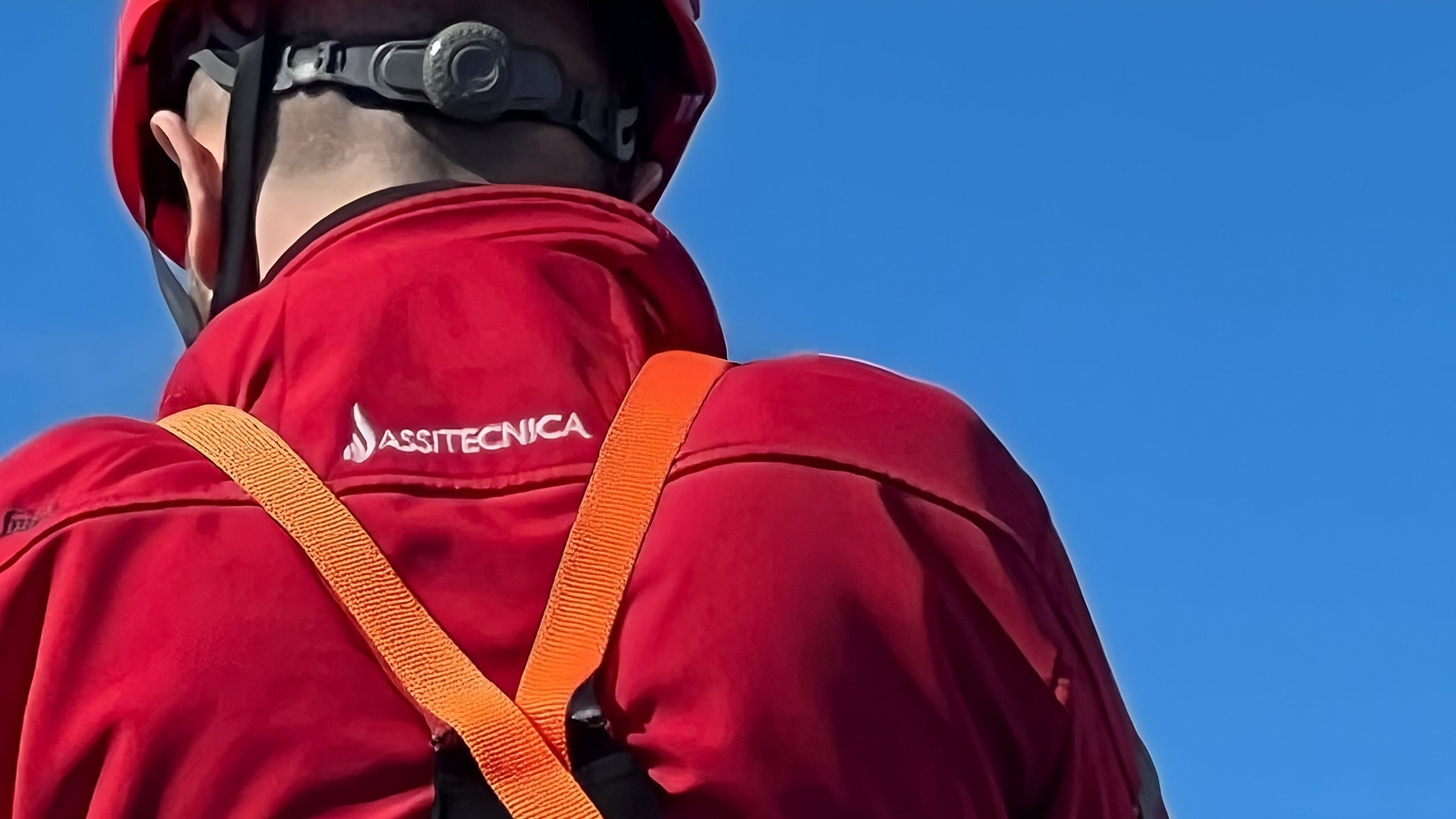 operatore assitecnica equipaggiato con felpa con logo in evidenza assitecnica srl, caschetto di protezione e imbracatura