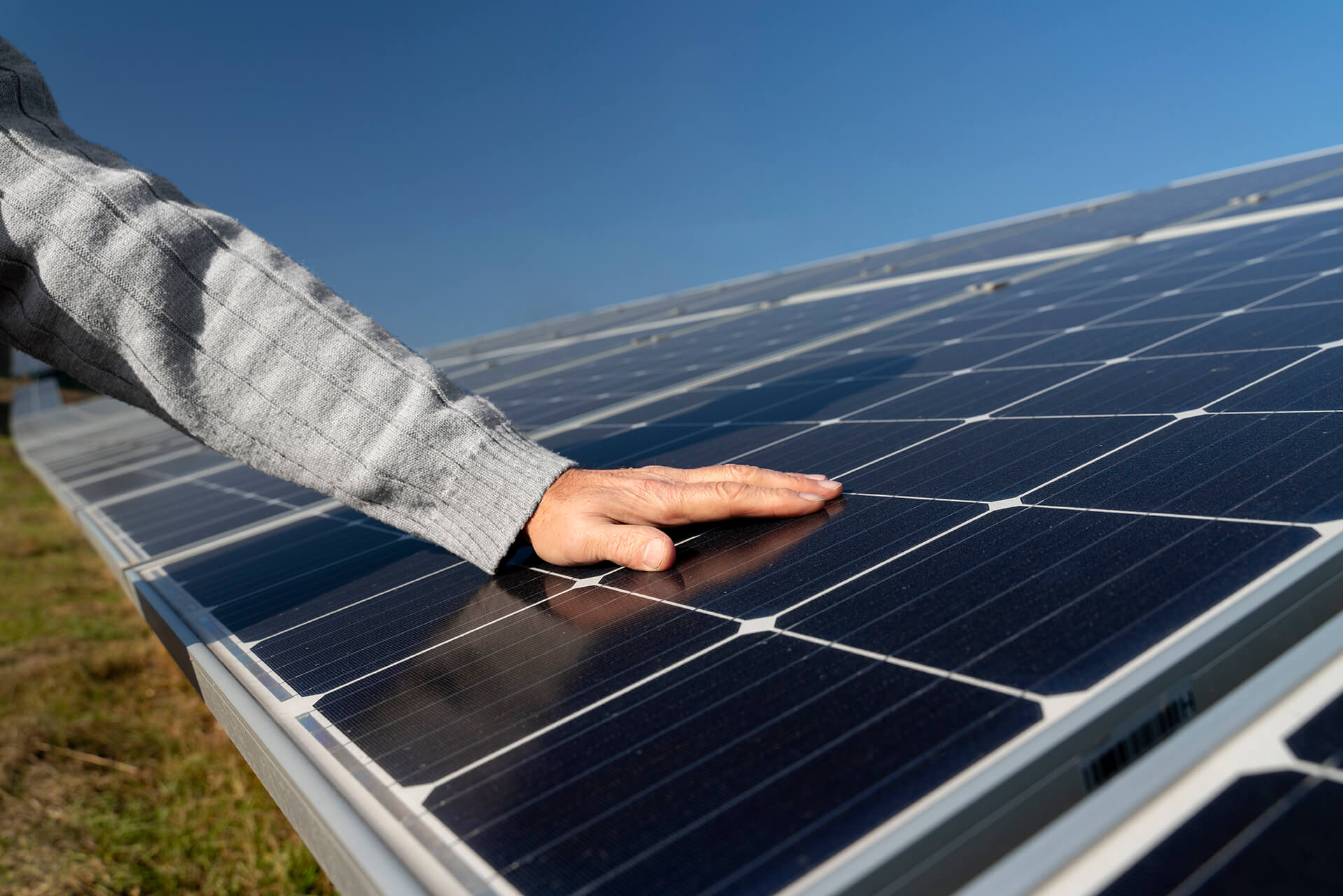 operatore assitecnica che appoggia la mano sinistra sopra un pannello fotovoltaico nuovo e pulito dopo installazione