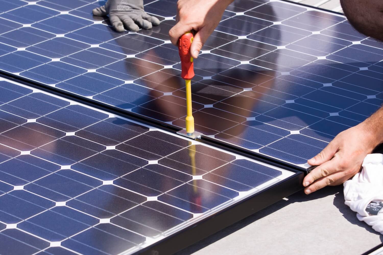 tecnico assitecnica durante installazione di un pannello fotovoltaico utilizzando un cacciavite per dadi